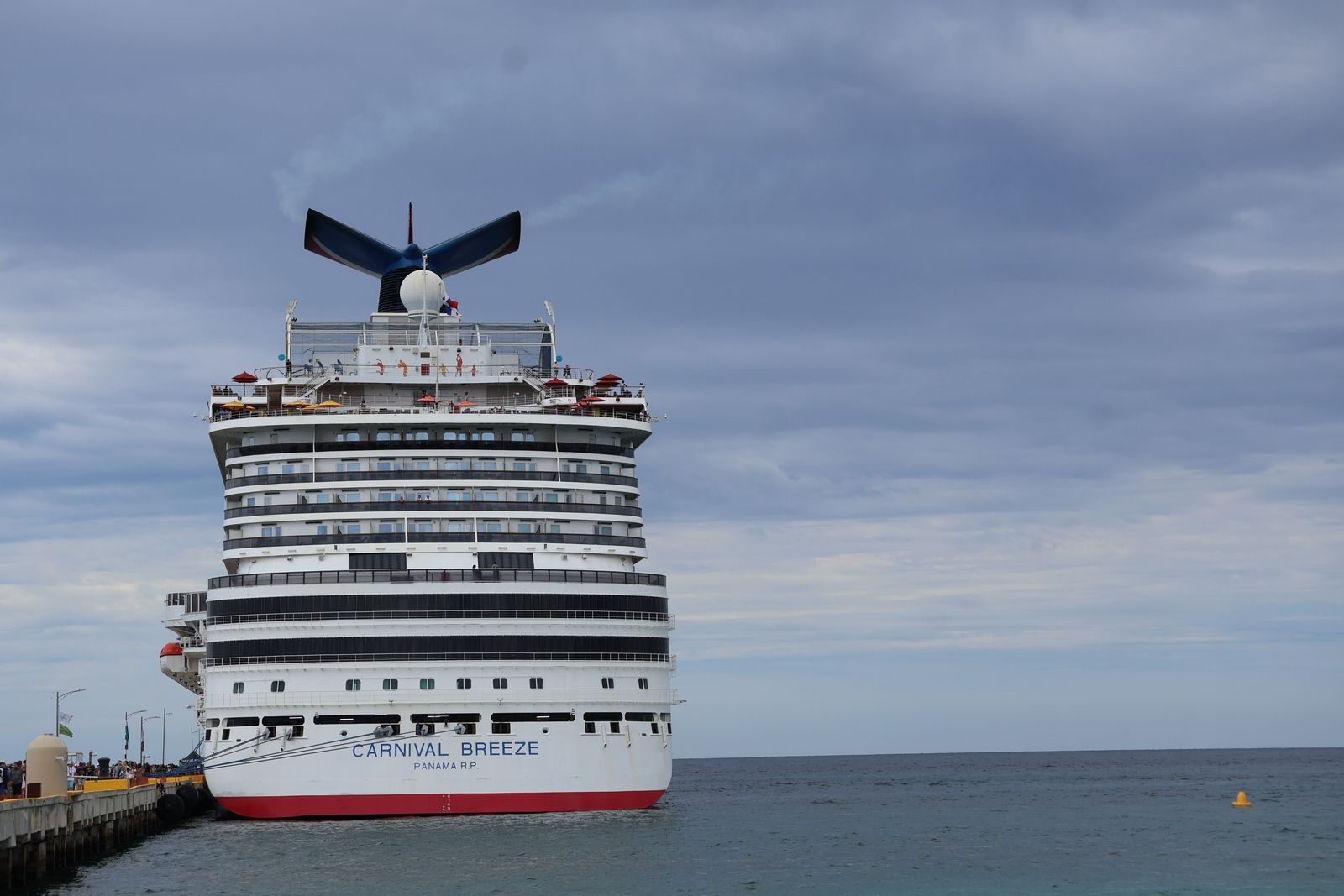 Carnival Breeze seen bow-on at a pier with its red-white-and-blue winged funnel, smaller sister of the biggest Carnival ship