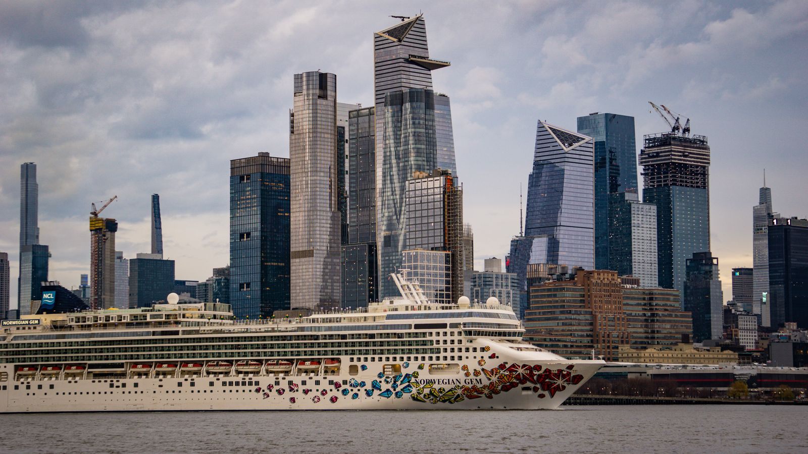 Norwegian Cruise Line ship with a painted hull sailing past the Manhattan skyline