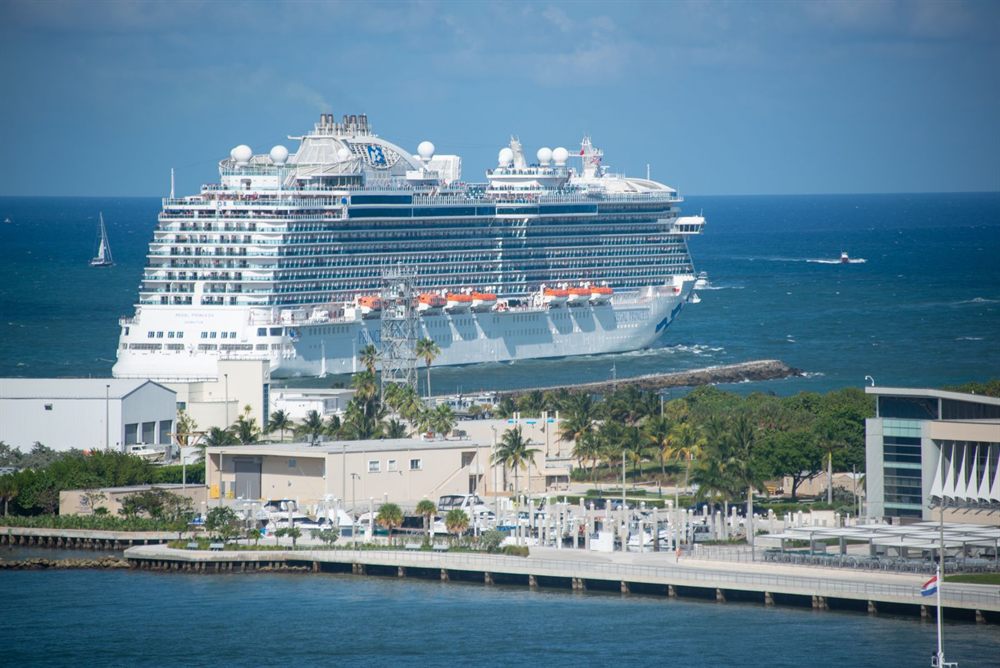 Large cruise ship berthed beside a modern cruise terminal at a tropical port